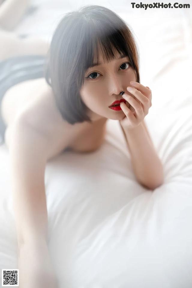 A woman laying on top of a bed with a cigarette in her mouth.