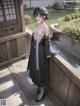 A woman in a black kimono standing on a wooden deck.