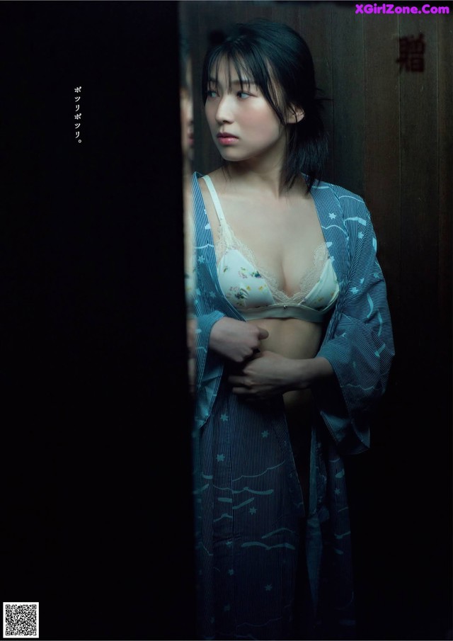 A woman in a blue kimono standing in front of a mirror.