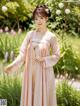 A woman in a pink hanbok standing in a garden.