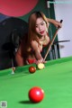 A woman in a red bikini playing pool.