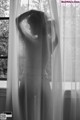 A naked woman standing in front of a window.