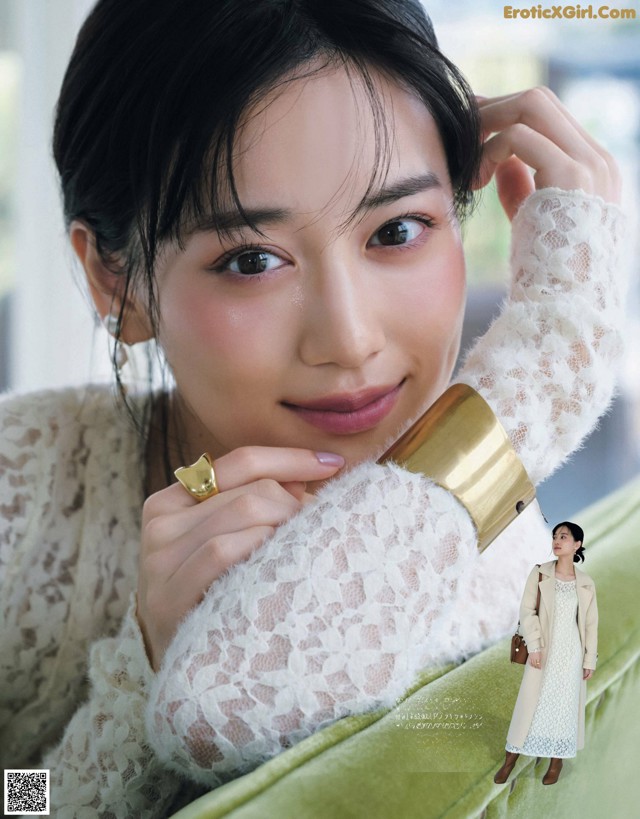 A woman in a white dress sitting on a green couch.