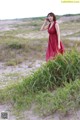 A woman in a red dress standing in the sand.