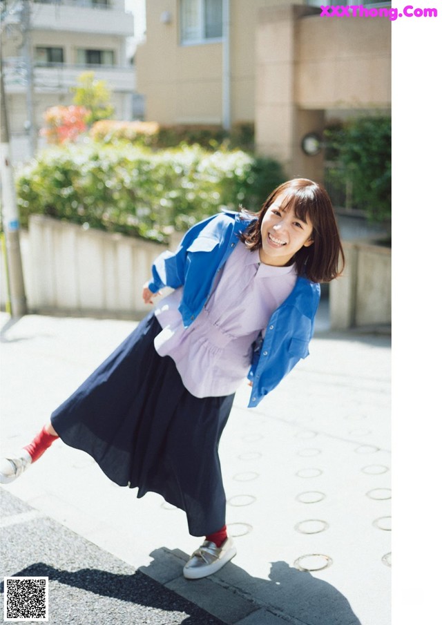 A woman in a blue jacket and black skirt is dancing.